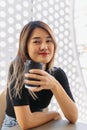 Happy woman in black t-shirt sipping hot coffee in white coffee shop. Royalty Free Stock Photo