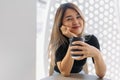 Happy woman in black t-shirt sipping hot coffee in white coffee shop. Royalty Free Stock Photo