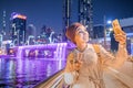 Woman blogger takes a beautiful selfie photo against the background of an artificial waterfall illuminated in neon light