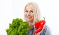 Happy woman with blond hair and beautiful smile holds red pepper and green lettuce in her hands for a healthy diet with Royalty Free Stock Photo