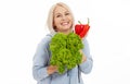 Happy woman with blond hair and beautiful smile holds red pepper and green lettuce in her hands for a healthy diet with Royalty Free Stock Photo