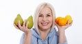 Happy woman with blond hair and beautiful smile holds two oranges, lemon and a pears in her hands for a healthy diet with