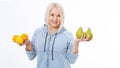 Happy woman with blond hair and beautiful smile holds two oranges, lemon and a pears in her hands for a healthy diet with