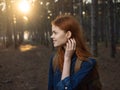 Happy woman in a blue shirt travels in a pine forest and the sunset in the distance