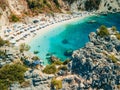 happy woman in blue swimsuit holding greece flag at the top of the cliff