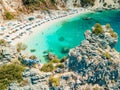 happy woman in blue swimsuit holding greece flag at the top of the cliff