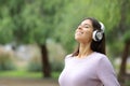 Happy woman breathing with headphones on green Royalty Free Stock Photo