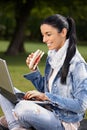 Happy woman browsing internet in park eating Royalty Free Stock Photo