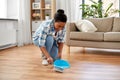 Happy woman with brush and dustpan sweeping floor