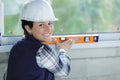 Happy woman builder measuring level window