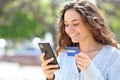 Happy woman buying online with credit card in the street Royalty Free Stock Photo