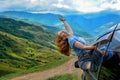 Happy woman in a car on a background of mountains. Summer vacation concept, tourism, travel, vacation Royalty Free Stock Photo