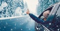 Happy woman in the car gesture finger up on the snowy background.