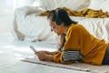 Happy woman in casual yellow clothing lying down floor and using phone for video call at her home. Person having leisure time