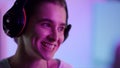 Happy woman celebrating victory in neon room closeup. Smiling girl take headset