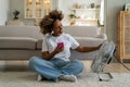 Happy woman chatting on mobile phone while relaxing in front of electric fan at home Royalty Free Stock Photo