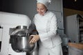 Happy woman chef baker using automated dough mixing machine