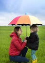 Happy woman and child opposite each other under one bright umbrella Royalty Free Stock Photo