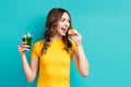 Happy woman choose unhealthy tasty cake holding smoothie detox juice on blue background