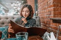 Woman chooses food and drinks from a large menu in a restaurant Royalty Free Stock Photo