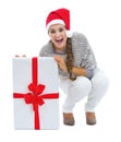 Happy woman in christmas hat sitting near big christmas present Royalty Free Stock Photo