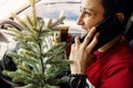 Happy woman with Christmas tree is talking on phone in car while drinking coffee Royalty Free Stock Photo