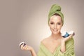 Happy woman with clean fresh skin hold a different of face care creams, wearing in bathrobe and towel on head Royalty Free Stock Photo