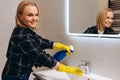 Happy woman cleaning in the bathroom. Washes the sink Royalty Free Stock Photo