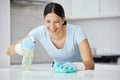 Happy woman cleaning home kitchen, spray product cleaner with safety gloves and polish table with cloth. Domestic