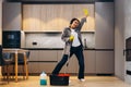 Happy woman cleaning home, singing at mop like at microphone and having fun, copy space. Housework, chores concept Royalty Free Stock Photo