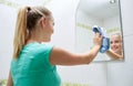 Happy woman cleaning mirror with rag Royalty Free Stock Photo