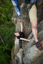 Happy woman climbing rock trekking outdoors. Carefree hiker smiling her friend. Friendly helping hand