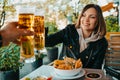 Happy woman clink beer glasses with man in asian cafe in Germany. Positive lady during oktoberfest celebration.