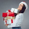 Happy woman with closed eyes holding pile of christmas gifts.