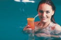 Happy woman with cocktail in water.