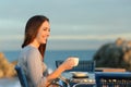 Happy woman contemplating in a coffee shop on the beach