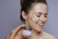 happy woman with cosmetic cream jar isolated on blue background Royalty Free Stock Photo