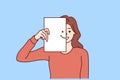 Happy woman covers half of face with paper with smiling emoticon, wanting to share good mood Royalty Free Stock Photo