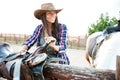 Happy woman cowgirl smiling and preparing saddle for riding horse Royalty Free Stock Photo