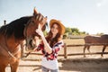 Happy woman cowgirl taking care of her horse on ranch Royalty Free Stock Photo