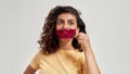 Happy woman with curly hair holding purple film in front of her mouth, smiling away, posing isolated over light