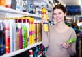 happy woman customer deciding on hair care products in shop Royalty Free Stock Photo