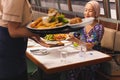 Happy woman customer with smile while getting food from waitress in restaurant.