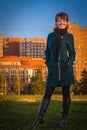 Happy woman in a dark coat standing outdoors autumn at sunset