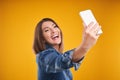 Close up of woman in denim jacket with smartphone over yellow background Royalty Free Stock Photo