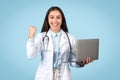 Happy young woman doctor with computer, success gesture Royalty Free Stock Photo