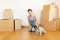 Happy woman with dog and boxes moving to new home Royalty Free Stock Photo