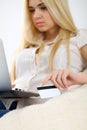 Happy woman doing online shopping at home . Close- up of a hand holding a credit card next to a laptop Royalty Free Stock Photo