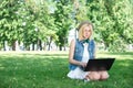 Happy woman downloading music outdoors with laptop