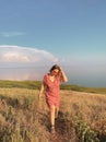 Happy woman in dress walking on country road along sea coast during summer vacation on sunny day Royalty Free Stock Photo